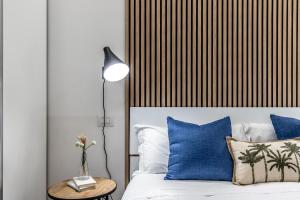 1 dormitorio con 1 cama con almohadas azules y lámpara en StayEasy Quadronno33 - 3 bedrooms, 2 baths - Duomo walking distance, en Milán