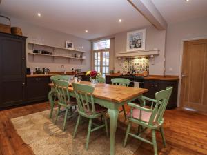 Una cocina con una mesa de madera y sillas verdes. en 11a Market Cross Place, en Aldeburgh