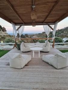 a patio with white couches and a table on a wooden deck at KERAME PARADISE VILLA in Agios Kirykos