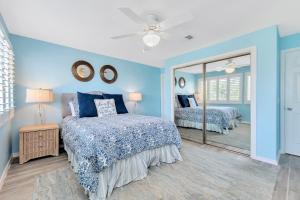een blauwe slaapkamer met 2 bedden en een spiegel bij Needle Rush Point Unit G21 in Pensacola