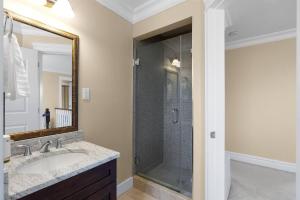 een badkamer met een douche, een wastafel en een spiegel bij Lianhua Cottage in Richmond