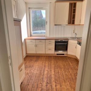 cocina con armarios blancos y suelo de madera en Weber Apartment David, en Bramsche
