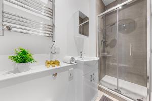 a white bathroom with a shower and a sink at Stylish One Bedroom Flat - Sleeps 3 - Near Heathrow, Windsor Castle, Thorpe Park - Staines London TW18 in Staines upon Thames