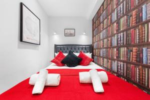 una camera con un grande letto rosso e librerie di Stylish One Bedroom Flat - Sleeps 3 - Near Heathrow, Windsor Castle, Thorpe Park - Staines London TW18 a Staines upon Thames