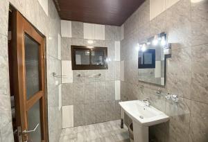 La salle de bains est pourvue d'un lavabo, d'une douche et d'un miroir. dans l'établissement Double twins Hotel & appartement, à Yaoundé