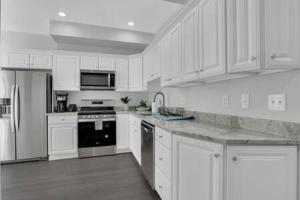 a white kitchen with white cabinets and appliances at Bartram Dream House I - Bartram Beach Retreat in Atlantic City