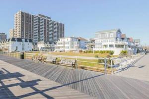 a boardwalk with benches on a beach with buildings at Bartram Dream House I - Bartram Beach Retreat in Atlantic City