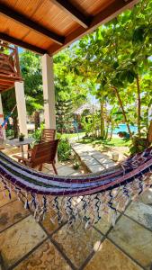 a hammock on a patio with a chair and a table at Casa Suiça Brasileira in Jericoacoara