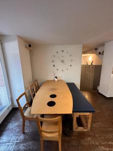 una mesa de madera con sillas y un reloj en la pared en Stay2Night City Center Hostel, en Zúrich