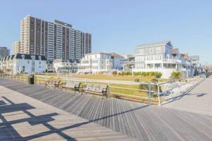 a boardwalk with benches on a beach with buildings at Bartram Dream House II - Bartram Beach Retreat in Atlantic City