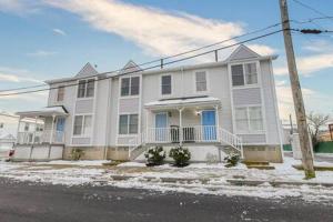 una casa blanca con una puerta azul en la nieve en Board Game Bungalow - Quiet Neighborhood in AC! en Atlantic City