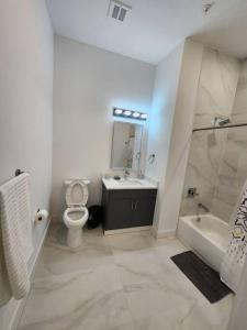 La salle de bains est pourvue de toilettes, d'un lavabo et d'un miroir. dans l'établissement Close to NYC - 2Bed Vast Stylish Apt, à Bayonne