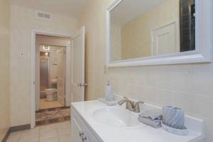een witte badkamer met een wastafel en een spiegel bij Escape to Raleigh Ave Glamour - Steps to the Beach in Atlantic City
