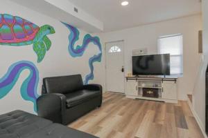 a living room with a couch and a fish painted on the wall at Arcade Nook & New Sea Turtle Mural- 3BR in Atlantic City