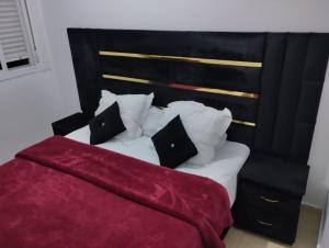 a bedroom with a bed with red sheets and pillows at Appartement du luxe in Ifrane