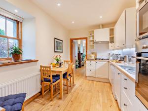 a kitchen with white cabinets and a table and chairs at 2 Bed in Coldingham 93242 in Duns