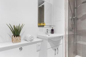 y baño blanco con lavabo y ducha. en Modern One Bedroom Flat - Near Heathrow, Windsor Castle, Thorpe Park - Staines London TW18 en Staines upon Thames