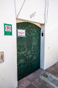 eine grüne Tür in einem Gebäude mit einem Schild drauf in der Unterkunft Dragonfly Guest House in Sucre