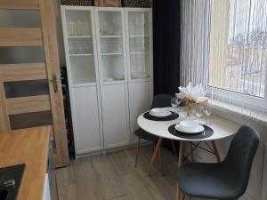 a kitchen with a table and chairs and a white cabinet at Apartament Kościuszki Iława in Iława