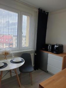 a room with a table and a kitchen with a window at Apartament Kościuszki Iława in Iława
