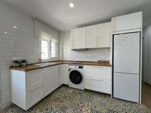 cocina con armarios blancos, lavadora y secadora en The Traveller`s house con vistas a PLAYA LA CALETA, en Cádiz