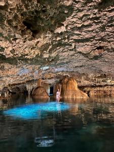 a woman standing in the water in a cave at Malakai Hostel in Tulum