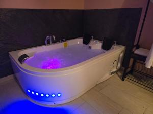 a white bath tub with blue lights in a bathroom at Suite Love et Evasion in Saint-André-le-Gaz