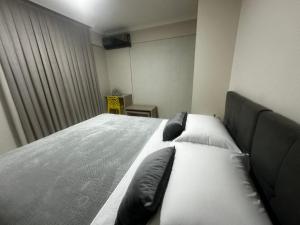 Un dormitorio con una cama grande con almohadas. en APTO no Centro, COMPLETO, UNIPAR e SHOPPING JL en Cascavel