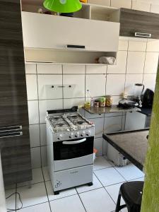 a white kitchen with a stove and a counter at Quarto acolhedor em apto com ótima localização. in São Luís