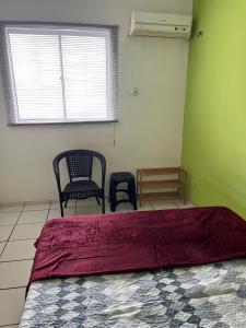 a bedroom with a bed and two chairs and a window at Quarto acolhedor em apto com ótima localização. in São Luís