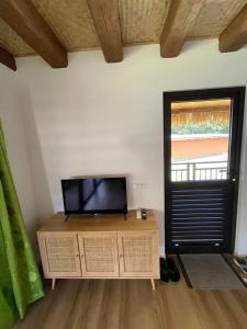 a living room with a tv and a wooden cabinet at Bungalow Faré Miti Vairao in Vairao