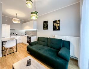 a living room with a green couch and a kitchen at Wygodne Mieszkania Nova Mikołowska 135 in Katowice
