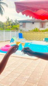 uma pessoa segurando duas taças de champanhe perto de uma piscina em Villa BEAUCI-TURLET em Goyave