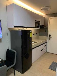 a kitchen with a black refrigerator and white cabinets at JAMAHSA CONDO STAYCATION TREES RESIDENCES NEAR SM FAIRVIEW in Manila