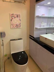 a bathroom with a toilet with a black seat and a sink at JAMAHSA CONDO STAYCATION TREES RESIDENCES NEAR SM FAIRVIEW in Manila