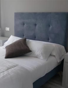 a bed with a blue headboard and white pillows at El Silencio de Galadhrim in Ponferrada