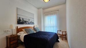 a bedroom with a bed with a blue blanket and a window at TERRAMAR sweet home in Villajoyosa +25 photos