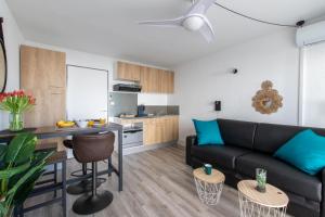 un salon avec un canapé noir et une cuisine dans l'établissement L'Éden des Vacances * clim * Terrasse * wifi *Port, à La Grande Motte