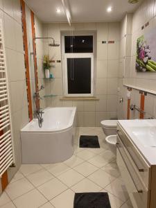 a white bathroom with a tub and a toilet at Modern & cozy Rooms Leipzig-Gohlis in Leipzig