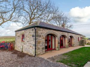 - un petit bâtiment en pierre avec des fenêtres rouges sur un champ dans l'établissement 2 Bed in Allendale 78158, à Catton
