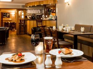 Sandhead的住宿－Tigh Na Mara Hotel，一张桌子,上面放着两盘食物和一杯葡萄酒