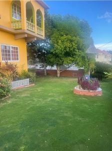 um quintal com uma casa amarela com uma varanda em The Manor Deluxe Suite em Ocho Rios