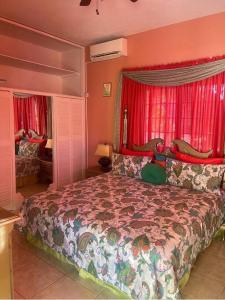 a bedroom with a large bed with red curtains at The Manor Deluxe Suite in Ocho Rios