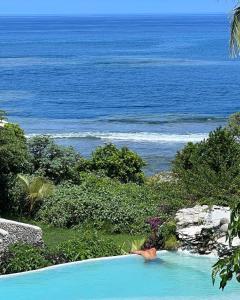 a person laying in a swimming pool overlooking the ocean at Tanna Evergreen Resort & Tours in Tanna Island