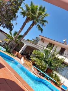a pool in front of a house with palm trees at Villa Aladin in Sciacca