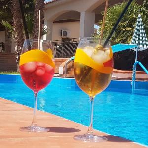 two wine glasses sitting next to a swimming pool at Villa Aladin in Sciacca