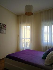 a bedroom with a bed with purple sheets and windows at Mirador de las cigüeñas in Zamora