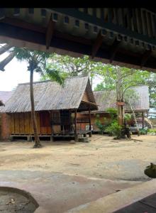 een gebouw met een rieten dak en een palmboom bij Sanctuary Lanta in Koh Lanta