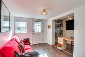 a living room with a red couch and a table at Eclectic Stone Cottage, Walk to Downtown Staunton! in Staunton