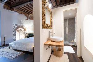 una camera da letto con lavandino, letto e specchio di centro storico - LUXURY EXPERIENCE NARNI VINTAGE ÉLITE SUITE a Narni
